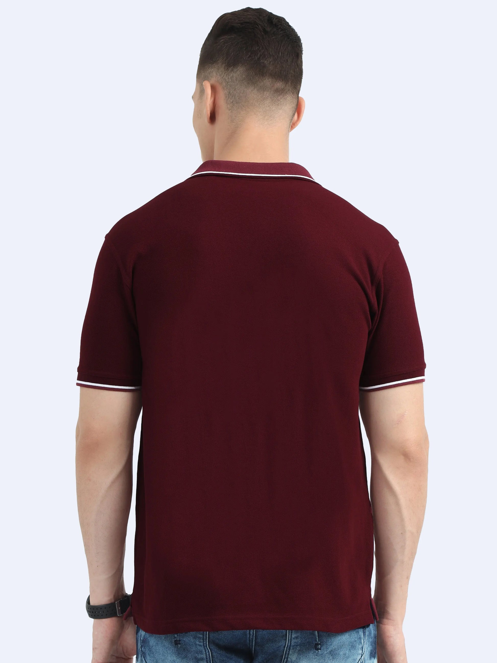 Back view of man wearing maroon polo t-shirt with white trim and blue jeans