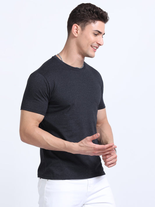 Man wearing a plain black crew neck t-shirt and white pants on a white background