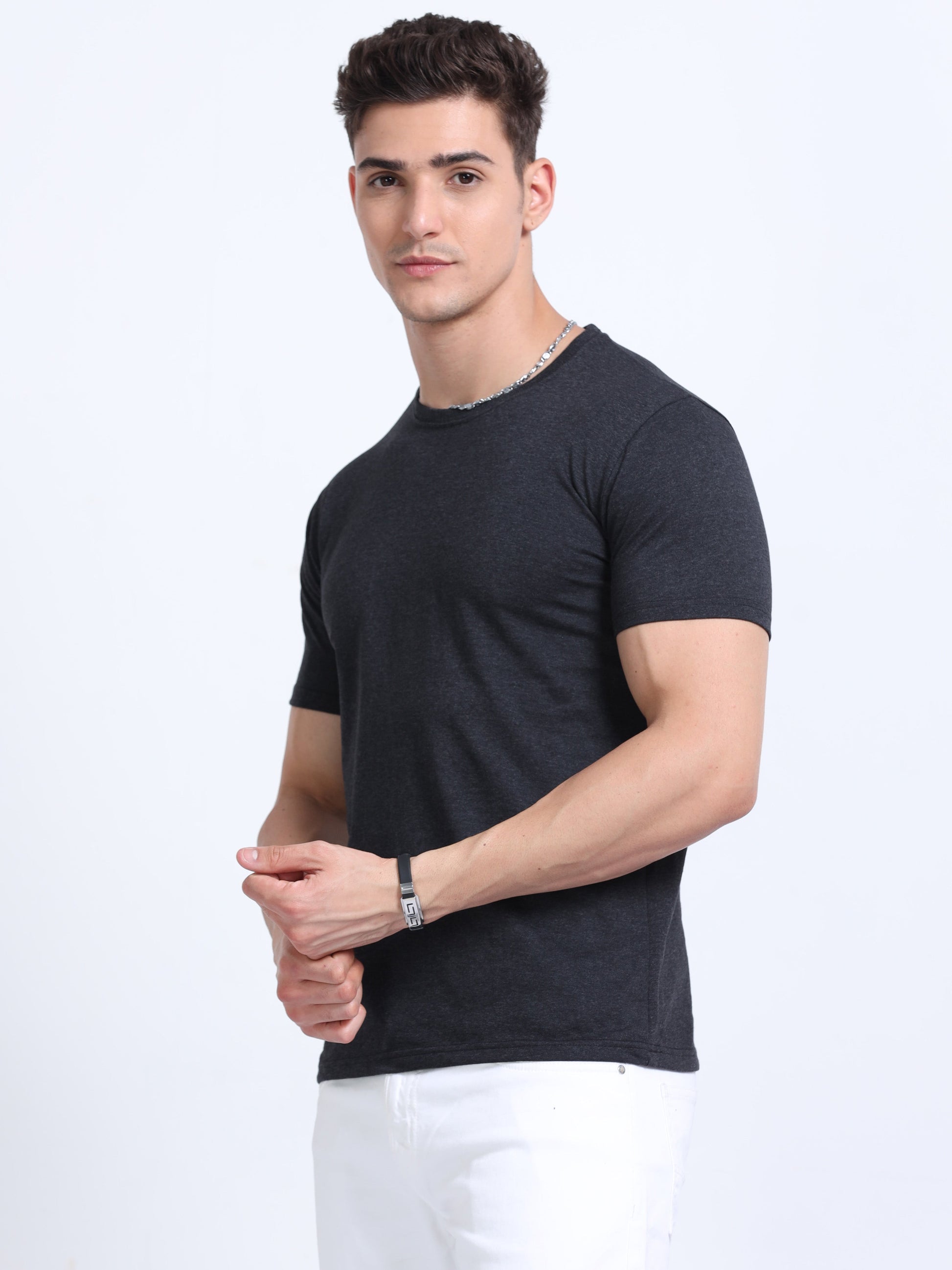 Man wearing plain black crew neck t-shirt and white pants, studio background